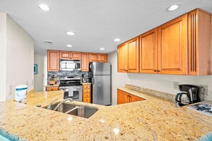 A kitchen with granite countertops, stainless steel appliances, wooden cabinets, and a built-in microwave.