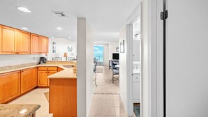 A modern kitchen with wooden cabinets, a granite countertop, and a view to the living area.