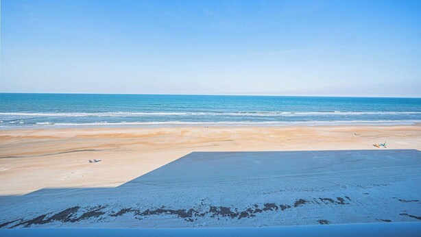 A beach with a clear sky and calm sea.