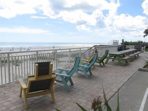 A beachside patio with outdoor seating and a view of the ocean. - Southpoint 506 in Ponce Inlet, FL (Ponce Inlet)
