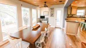 A spacious kitchen with a long wooden table, white chairs, and a ceiling fan. - Lakefront Home Close to the Beach! Sleeps 16 (Santa Rosa Beach)
