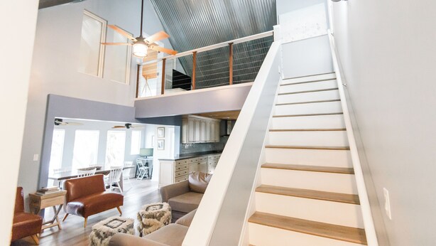 A spacious living area with a high ceiling, a staircase, and a kitchen in the background. - Lakefront Home Close to the Beach! Sleeps 16 (Santa Rosa Beach)