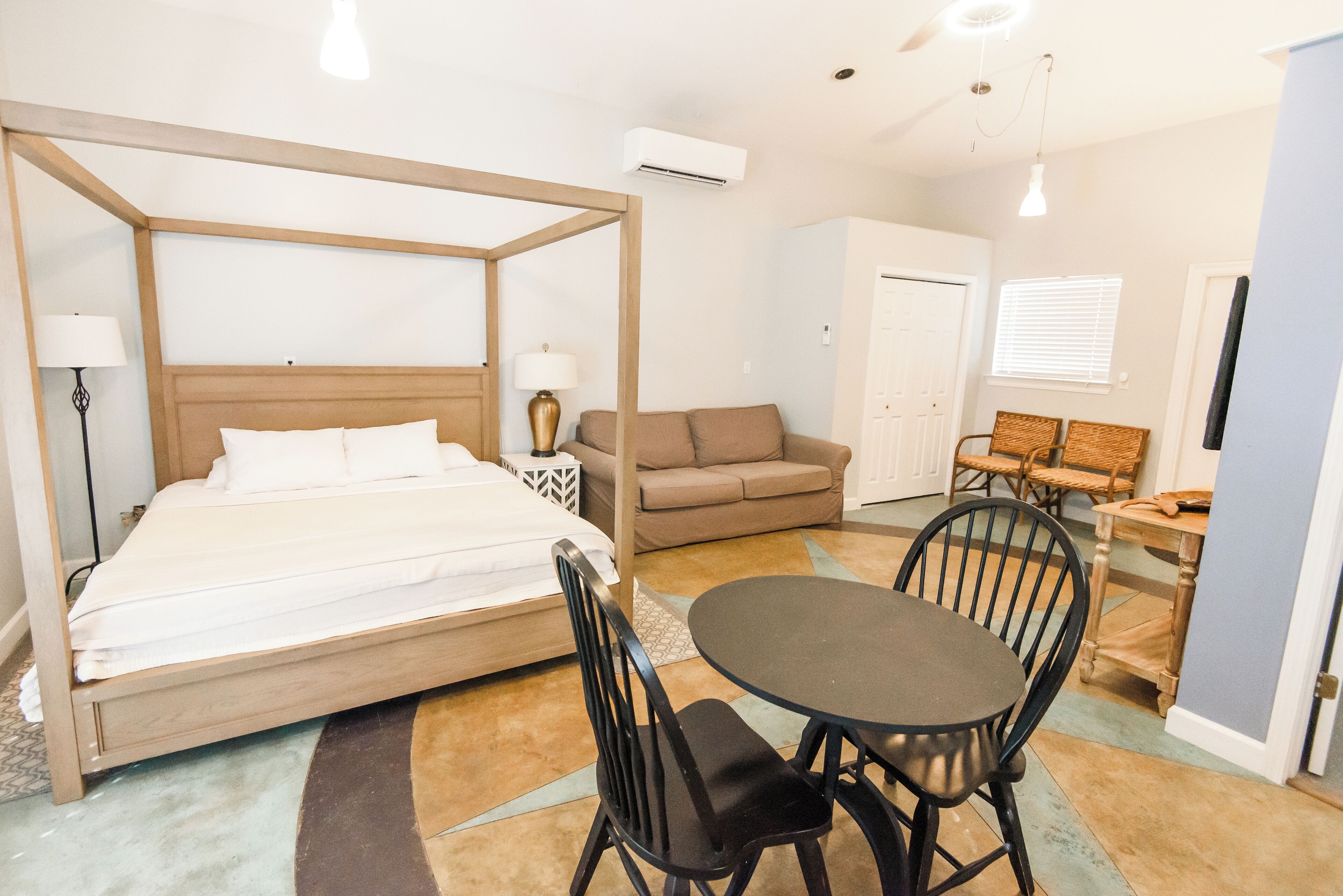 Ein Schlafzimmer mit Himmelbett, einer Couch, einem Esstisch mit Stühlen und einer kleinen Küchenzeile.