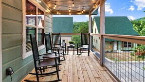 Eine Holzterrasse mit Stühlen und einem Tisch, mit Blick auf eine grüne Landschaft.