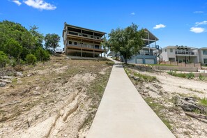 A multi-story building with a concrete pathway leading to it, surrounded by trees and a clear sky.