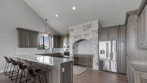 A modern kitchen with a large island, bar stools, and stainless steel appliances. - “WATERS-EDGE” A WATERFRONT home! Hot Tub!! VIEWS!!! (Canyon Lake)