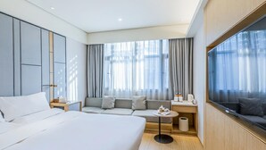A hotel room with a large bed, a sofa, a TV, and a window with curtains. - JI Hotel (Hangzhou West Lake Hubin Jiefang Road) (Hangzhou)