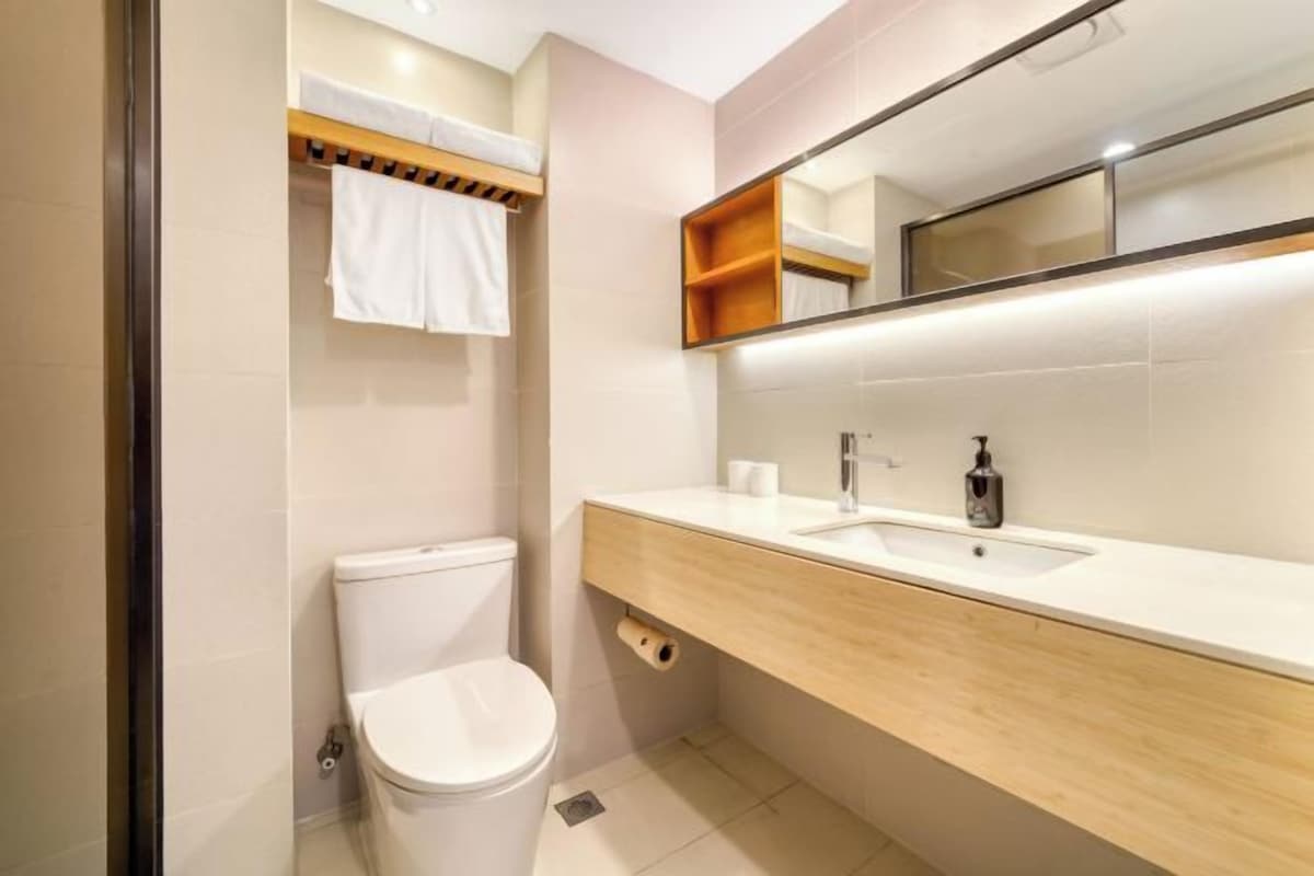 A modern bathroom with a toilet, sink, and mirror.