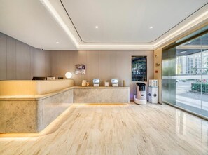 A modern reception area with a marble counter, digital check-in stations, and a view of the street through large windows. - JI Hotel (Hangzhou West Lake Hubin Jiefang Road) (Hangzhou)