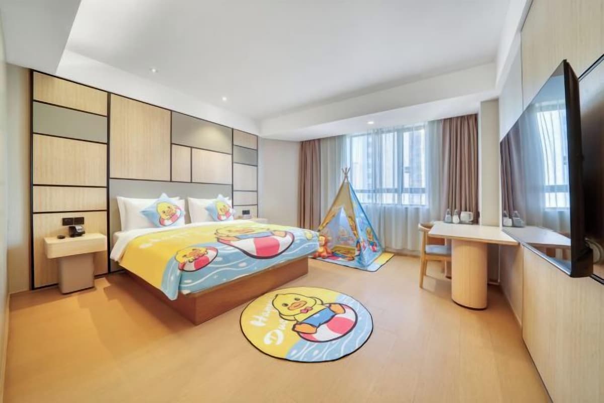 A hotel room with a bed, a desk, a TV, and a window.