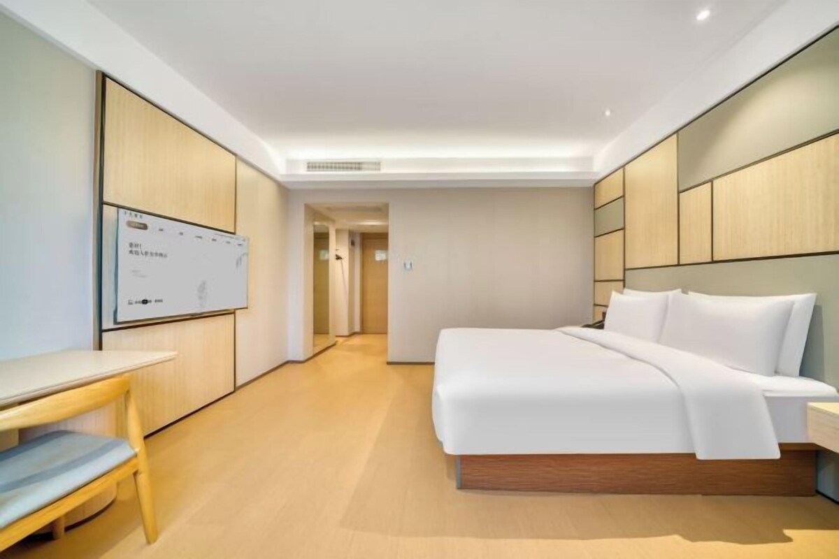 A hotel room with a bed, a desk, and a whiteboard.