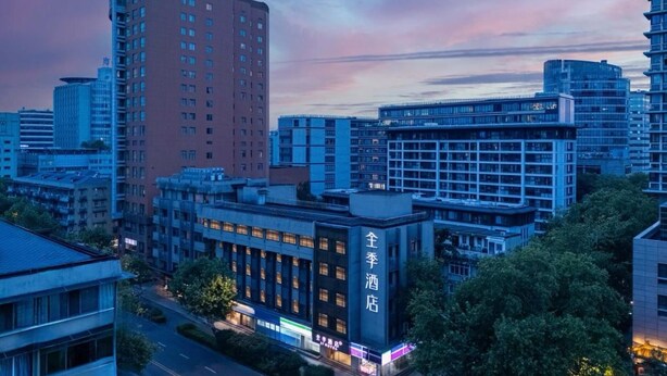 A hotel with multiple floors, a prominent sign, and a cityscape in the background. - JI Hotel (Hangzhou West Lake Hubin Jiefang Road) (Hangzhou)