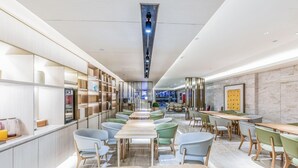 A modern interior with a central aisle, seating areas on both sides, and a vending machine. - JI Hotel (Hangzhou West Lake Hubin Jiefang Road) (Hangzhou)