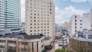 Ein mehrstöckiges Hotel mit einheitlicher Fassade, zahlreichen Fenstern und einem Parkplatz im Vordergrund.