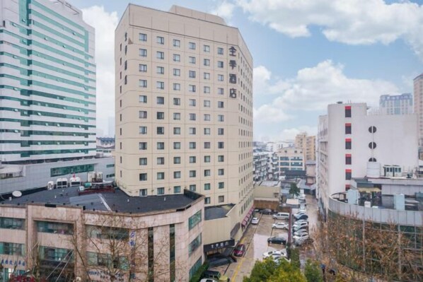 Un hôtel à plusieurs étages, doté d’une façade uniforme, de nombreuses fenêtres et d’un parking situé en avant.