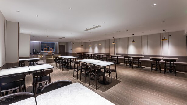 A modern restaurant interior with tables and chairs, recessed lighting, and a counter area. - Hanting Express Rugao Anding Square (Nantong)