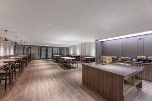 Eine moderne Hotelhalle mit einer langen Rezeption, mehreren Sitzbereichen und einem großen Fenster.