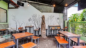 A restaurant interior with wooden tables and chairs, a concrete pillar, and a mural with abstract tree designs.