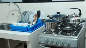 A compact kitchen with a gas stove, oven, and a sink with a dish rack.