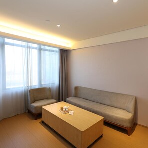 A modern hotel room with a sofa, armchair, and a wooden coffee table. - JI Hotel Shanghai Wujiaochang Shiguang Road (Shanghai)