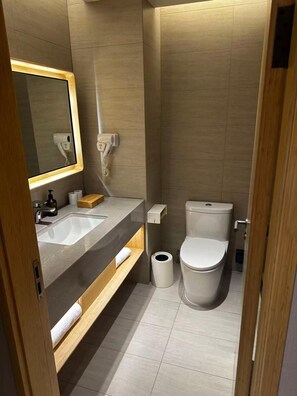 A modern bathroom with a sink, mirror, toilet, and a trash bin. - JI Hotel Shanghai Wujiaochang Shiguang Road (Shanghai)