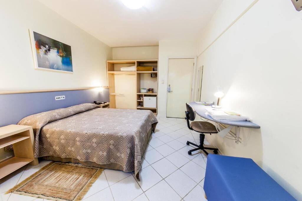 Une chambre à coucher comprenant un lit, une table de chevet, un bureau, une chaise et une armoire.
