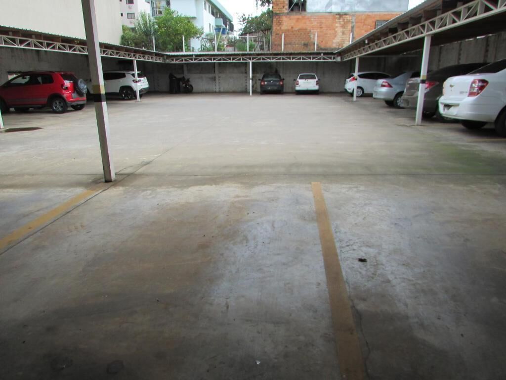A parking area with multiple cars parked under a covered structure.