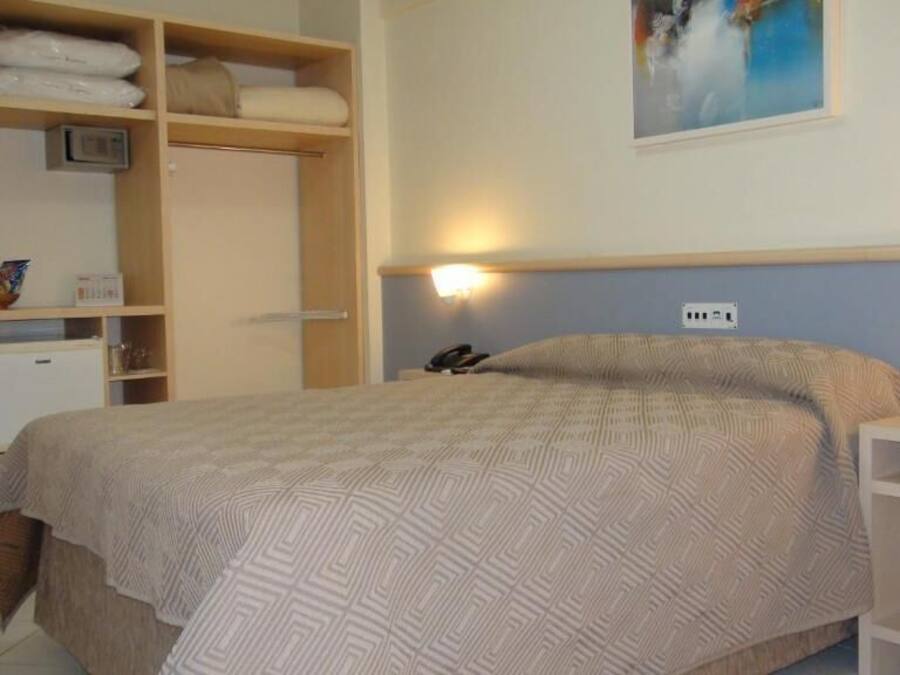 A bedroom with a bed, a bedside table, a wardrobe, and a wall-mounted light.