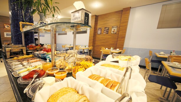 A buffet with various food items, including bread, fruits, and beverages. - Asppen (Chapecó)