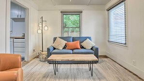 Ein Wohnzimmer mit einem blauen Sofa, einem Holztisch, einer Stehlampe und einem Deckenventilator.