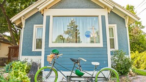 Una casa con fachada azul, un ventanal grande y una bicicleta estacionada adelante.