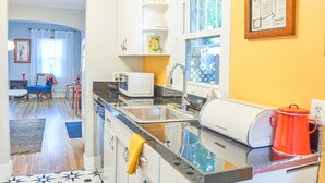 Una cocina pequeña con microondas, lavabo y una olla roja sobre la encimera.