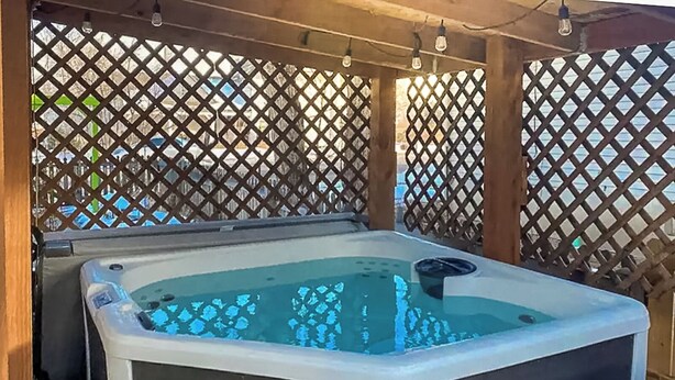 Un jacuzzi con un fondo de celosía de madera y una etiqueta de advertencia de seguridad.