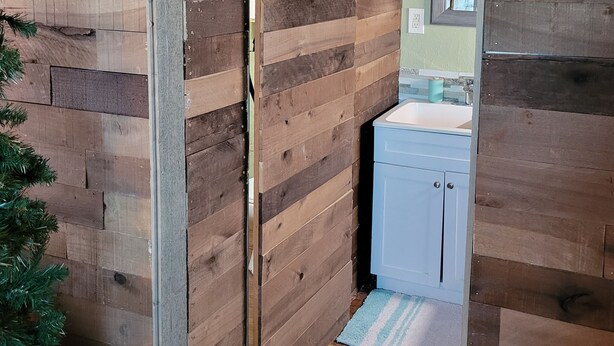 A wooden interior with a sliding door leading to a bathroom. - Cozy Tiny Cabin with a small porch and firepit. (Kempner)