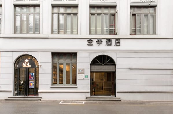 A building with a sign that reads '全季酒店' indicating a hotel. There are large windows with curtains, and a black entrance with glass doors. - JI Hotel Shanghai The Bund Jiujiang Road (Shanghai)
