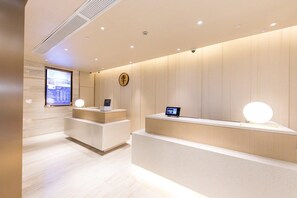 A modern reception area with a minimalist design, featuring a reception desk, digital display, and a clock on the wall. - JI Hotel Shanghai The Bund Jiujiang Road (Shanghai)