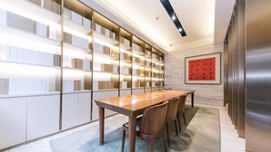 A modern conference room with a long wooden table, chairs, and a bookshelf with illuminated shelves. - JI Hotel Shanghai The Bund Jiujiang Road (Shanghai)