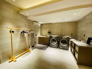 A modern laundry room with two washing machines, a drying rack, and a mirror. - JI Hotel Shanghai The Bund Jiujiang Road (Shanghai)