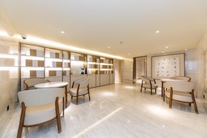 A modern interior with a long reception desk, marble flooring, and contemporary chairs. - JI Hotel Shanghai The Bund Jiujiang Road (Shanghai)