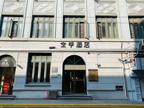 A hotel with a classic facade, featuring large windows and a prominent entrance with an arched doorway. - JI Hotel Shanghai The Bund Jiujiang Road (Shanghai)