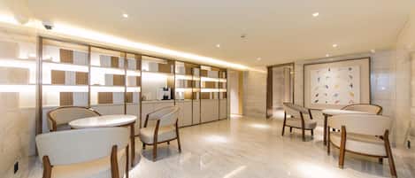 A modern interior with a long reception desk, marble flooring, and contemporary chairs.