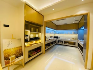 Uma cozinha de hotel moderna, com disposição organizada, equipada com diversos eletrodomésticos e espaço para armazenamento de alimentos e bebidas.