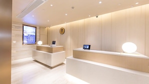 A modern reception area with a minimalist design, featuring a reception desk, digital display, and a clock on the wall. - JI Hotel Shanghai The Bund Jiujiang Road (Shanghai)