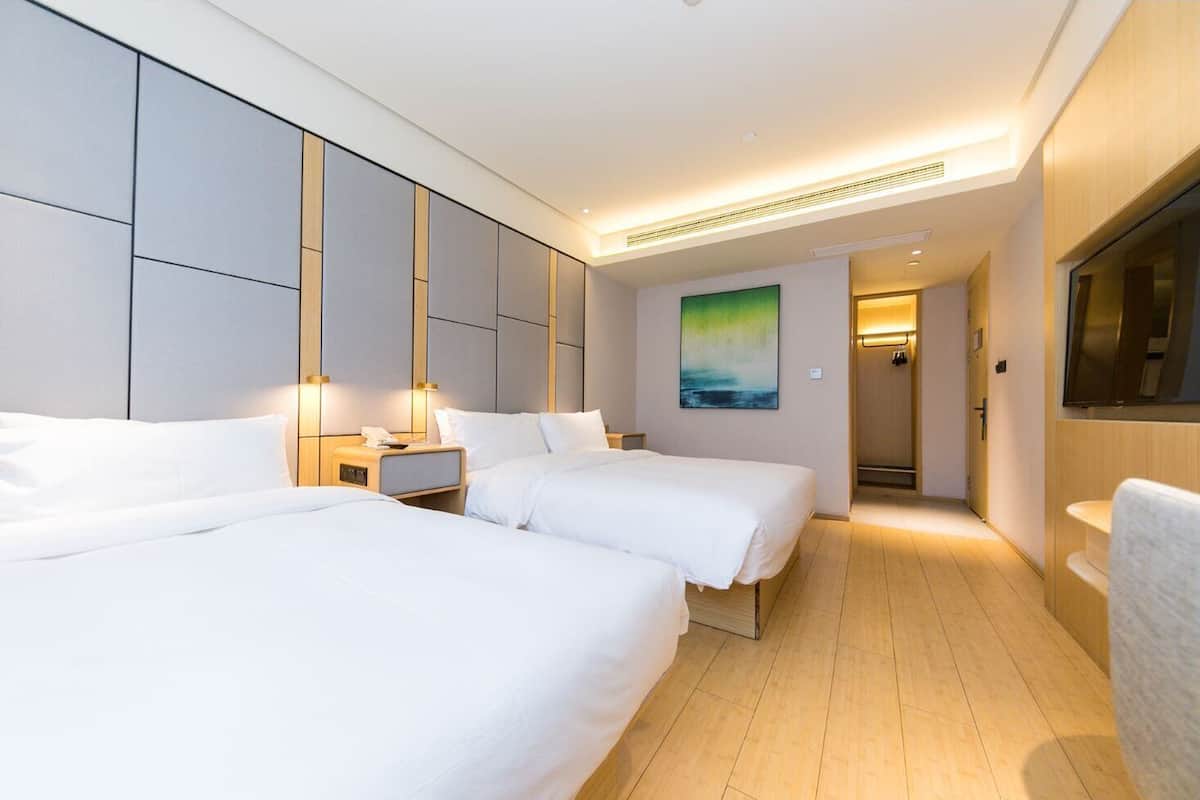 A hotel room with two beds, a nightstand, a painting, and a TV.