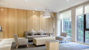 A modern living room with a sofa, two armchairs, a coffee table, and a floor lamp. - Ji Hotel (Shanghai)