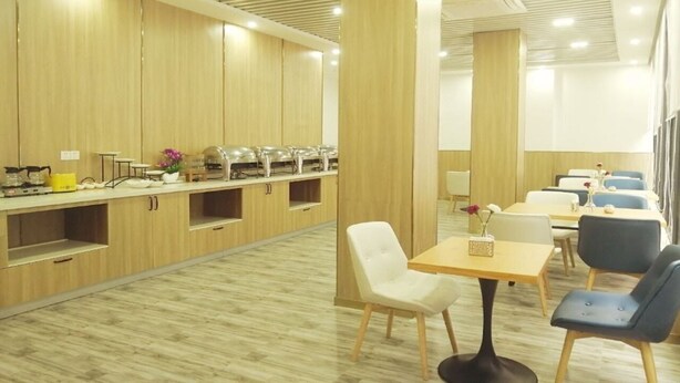 A modern dining area with wooden paneling, a buffet setup, and seating arrangements. - Hanting Hotel (Shenzhen)