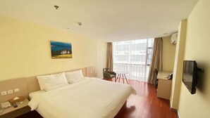 A hotel room with a large bed, a desk, a chair, a TV, and a painting on the wall. - Hanting Hotel (Shenzhen)