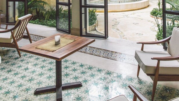 A spacious patio with a wooden table and chairs, large arched windows, and a view of the surrounding greenery. - TreeHouse Boutique Hotel - Adults Only  (Mérida)