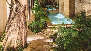 A nighttime outdoor area with a water feature, a tree, and a stone pathway. - TreeHouse Boutique Hotel - Adults Only  (Mérida)