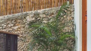 Un rincón con pared de piedra, valla de bambú y planta en maceta.